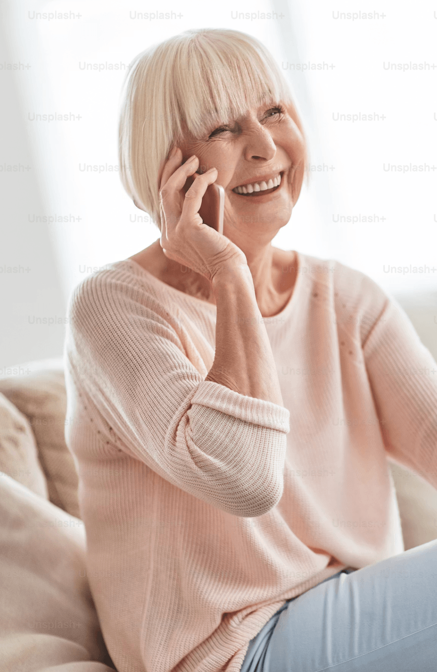 An older woman smiling while speaking with Coco by phone